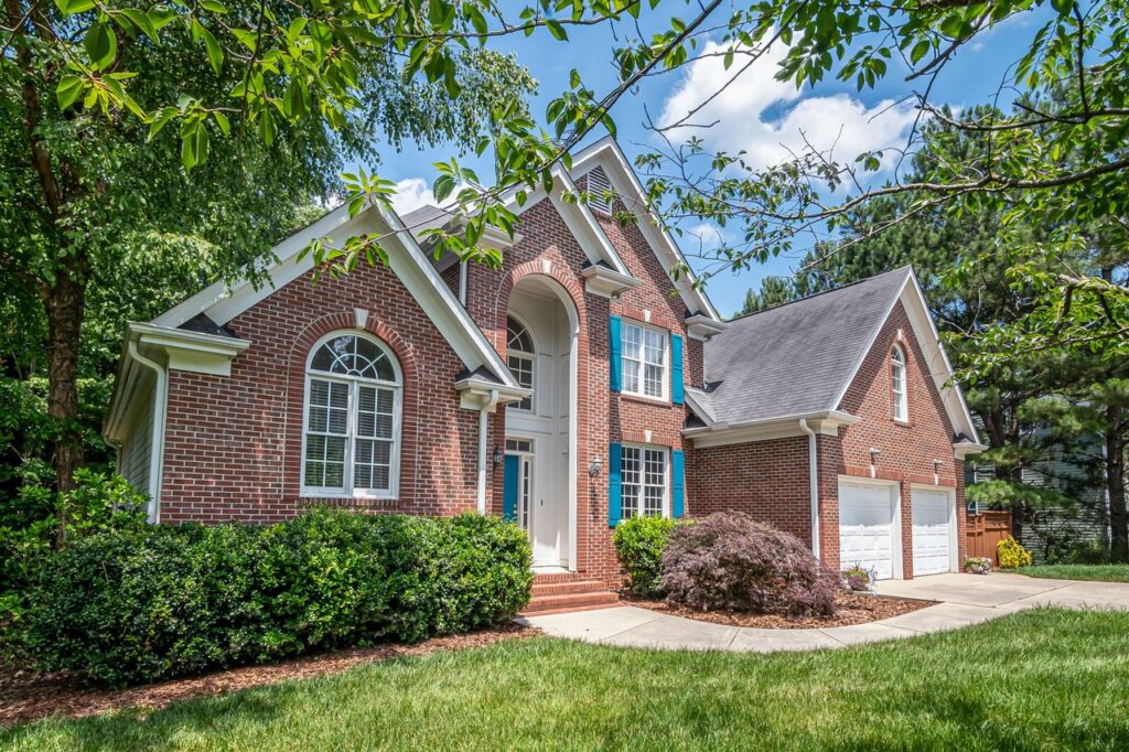 Beautiful brick suburban house surrounded by lush greenery, showcasing classic architecture.
